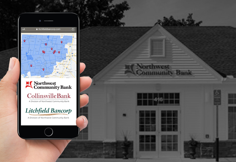 Hand holding an iPhone with Northwest Community Bank website loaded while standing in front of bank